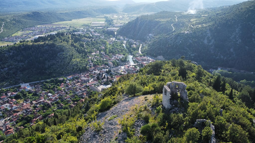 Da li ste ikada pomislili da se Stolac izgradio i razvio pod samotnim pogledom ove kamene građevine? Razvalina na ovom kršu nijemi je posmatrač i svjedok jedne ugasle carevine. Stoji kao spomenik onima koji su bdjeli nad gradom još prije nego što je postojao ovakav kakvim ga mi znamo. Na ovoj fotografiji prikazan je pogled na Stolac sa vrha Komanjeg Brda, gdje stara austrougarska osmatračnica i danas podsjeća da prošlost još uvijek gleda u nas.